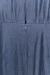 Vestido midi de color azul, confeccionado con lino. Presenta cuello redondo, manga sisa y diseño sin mangas. Cuenta con bajo asimétrico y detalle de vuelo en la parte frontal.