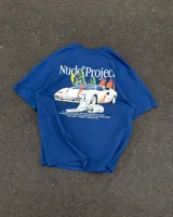 Remera azul marino de manga corta de la marca Nude Project, con cuello redondo y diseño gráfico en la espalda que incluye un auto deportivo en llamas, un perro dálmata y texto descriptivo.