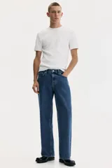 Jean de cinco bolsillos confeccionado en denim de algodón, con cintura estándar y cierre de botón. Presenta un corte relajado desde la cadera con pierna recta y amplia desde el muslo.