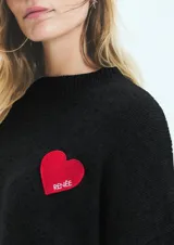 Sweater tejido negro con parche rojo en forma de corazón con la palabra RENÉE bordada en blanco.