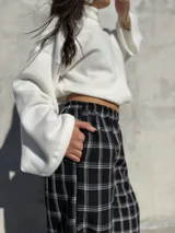 Pantalón de viyela con estampado de cuadrillé en blanco y negro. Presenta un diseño de silueta holgada con elástico en la cintura y en los puños, ofreciendo un estilo relajado y cómodo.