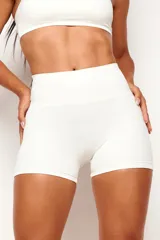 Short deportivo de cintura alta y diseño ajustado, color blanco crema, confeccionado en poliamida sin costura frontal.