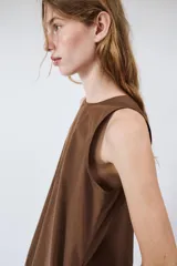 Vestido mini marrón de corte evasé con diseño tipo globo en el dobladillo, cuello redondo y mangas sisa. Presenta bolsillos laterales ocultos en la costura y cierre en la espalda con pequeña abertura y botón.