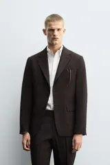 Blazer de corte regular confeccionado en tejido con lana, color marrón oscuro. Presenta cuello con solapas de muesca, cierre frontal de un botón, bolsillos con solapa en la cadera y bolsillo de vivo en el pecho.