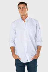 Camisa Oxford lisa de color celeste, con cuello abotonado, manga larga, cierre frontal de botones y un bolsillo aplicado en el pecho con detalle bordado.