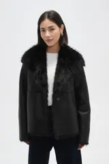 Chaqueta de eco-cuero negro con interior y cuello de piel sintética, diseño holgado, manga larga y cierre frontal con un botón.