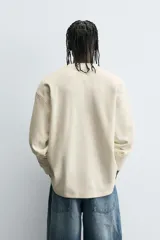 Camiseta de manga larga con cuello redondo, corte relaxed fit y tejido con estructura waffle. Presenta estampados y bordados combinados a contraste en el delantero.