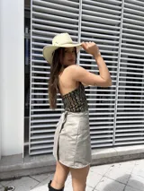 Minifalda gris cruzada de gamuza sintética, con hilera de ojales metálicos en la cintura.