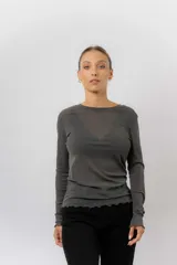Remera de manga larga en tejido liviano y translúcido color gris oscuro, con cuello redondo y terminaciones onduladas en ruedo y puños.