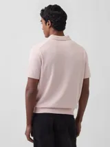 Buzo tipo polo de manga corta en tejido de punto color negro, con cuello y cierre frontal parcial con botones.
