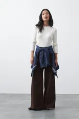 Polera de tejido de punto con textura calada y diseño de líneas verticales acanaladas. Presenta cuello alto y mangas largas con puños delicados, de silueta entallada.