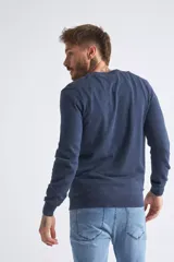 Sweater de tejido de punto color beige, con escote en V, mangas largas y puños y dobladillo acanalados. Presenta un pequeño logo bordado en el pecho.