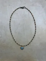 Collar de tres niveles compuesto por cuentas pequeñas de piedra natural y metal, con tres dijes en forma de corazón de piedra natural facetada en tonos rosado, negro y gris, enmarcados en metal dorado.