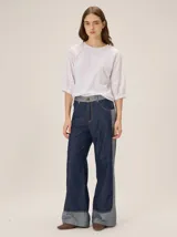 Pantalón de jean tiro medio-alto, corte wide leg con diseño bicolor en tonos azul oscuro y denim claro, bolsillos delanteros y traseros, y botamanga ancha.