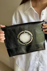 Sobre de mano color bordó en cuero charolado, con solapa frontal decorada con una piedra ágata natural engarzada. Incluye correa larga extraíble y cierre trasero.