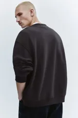 Buzo negro de cuello redondo con estampa frontal inspirada en la banda Ramones, hombros caídos y corte holgado.
