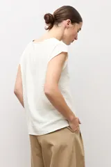 Blusa blanca con textura plumeti, de manga corta y cuello redondo.