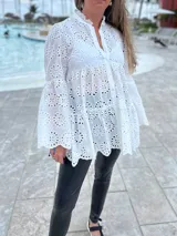 Camisa blanca de broderie con cuello mao, mangas largas amplias y cierre frontal con botones.