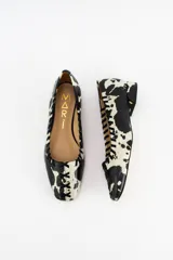Mocasines planos de cuero con estampado de vaca (cow print) en blanco y negro. Presentan detalles bordados en el empeine y en los laterales, con una puntera cuadrada y un pequeño taco de 2 cm.
