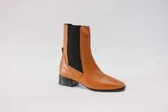 Botas de cuero color beige con elásticos laterales negros, taco cuadrado y punta cuadrada.