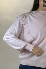 Buzo de hilo de punto fino en color rosado, con cuello redondo, mangas largas y detalle de volados en los hombros.