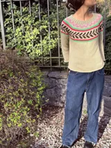 Sweater tejido a mano en hilo de algodón color beige con cuello redondo y diseño geométrico en el pecho en colores rosa, verde y marrón.