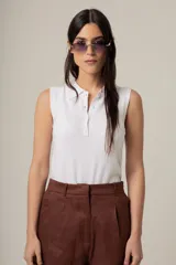 Top blanco sin mangas, con cuello polo y botones frontales.