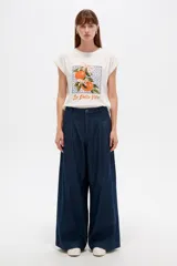 Remera de algodón color blanco, de corte holgado y manga corta con vuelta. Presenta un estampado frontal rectangular con naranjas, moños rosados y la leyenda "La Dolce Vita".