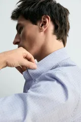 Camisa de corte relajado confeccionada en tejido de algodón con estampado de cuadros pequeños. Presenta cuello abotonado, cierre frontal con botones y manga larga con puños abotonados.