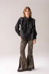 Camisa blanca de corte clásico con volados frontales y en los hombros, manga larga con puños abotonados y cierre frontal con botones.