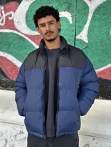 Campera puffer azul con canesú negro y cierre frontal.