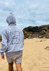 Hoodie gris con capucha y cordón ajustable, corte oversize y estampa en la espalda de una ola dentro de un recuadro.