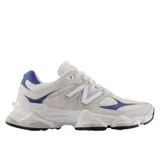 Championes urbanos New Balance modelo 9060, con diseño futurista inspirado en la estética de los años 2000. Presentan una combinación de tonos beige y blanco con detalles en azul, entresuela esculpida con tecnología de amortiguación ABZORB y SBS, y una capellada de materiales mixtos.