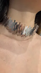 Gargantilla tipo choker rígida de metal plateado, compuesta por múltiples piezas verticales con diseño abstracto y acabado brillante.