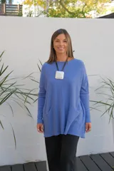 Sweater de punto color celeste, de corte holgado y largo, con mangas largas, cuello redondo y dos bolsillos frontales tipo parche.