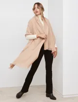 Bufandón tejido de poliéster, color rosa pálido con textura jaspeada en tonos pastel (naranja, lila, gris). Presenta un tejido grueso y flecos en los bordes.