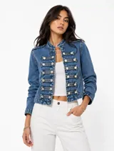 Chaqueta de denim estilo militar con cuello mao, cierre frontal con botones metálicos y detalles de trabillas horizontales. Presenta hombreras decorativas y diseño estructurado.