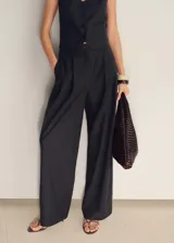 Pantalón de vestir de corte recto y tiro medio, confeccionado en tejido mezcla de algodón y lino con estampado de rayas verticales. Cuenta con cierre delantero de cremallera y botón, trabillas para cinturón y dos bolsillos laterales.