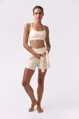 Top deportivo de soporte medio color beige claro con escote redondo y doble tirante en los hombros.