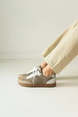 Championes marrones de cuero con cordones negros, puntera de charol y detalles dorados.