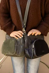 Cartera compacta de cuero color marrón, con diseño versátil y atemporal. Cuenta con un bolsillo exterior de gamuza con cierre y correa regulable con mosquetones metálicos.