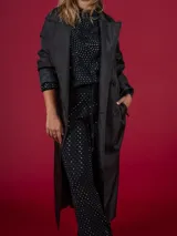 Trench negro con cuello solapa, doble botonadura y cinturón.