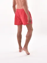 Short de baño color lila con estampado de palmeras blancas, cuenta con cintura elástica con cordón ajustable y bolsillos laterales.