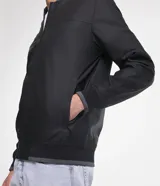 Campera bomber negra para hombre, confeccionada en material gomoso, con cuello alto, puños y bajo acanalados, y cierre frontal con cremallera.