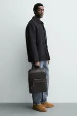 Mochila de diseño minimalista con acabado grabado, compartimento principal con cierre, espacio interior para dispositivos electrónicos de hasta 13 pulgadas, bolsillos frontales con cierre, parte posterior acolchada con banda de sujeción para equipaje, asa de mano y correas de hombro ajustables y acolchadas.