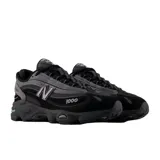 Championes urbanos New Balance modelo 1000, color negro con detalles en gris oscuro. Presentan un diseño técnico con capas superpuestas de malla y material sintético, logo N en el lateral y numeración 1000 bordada en la puntera. Cuentan con una suela robusta y amortiguada.
