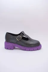 Zapato guillermina de cuero color negro con suela chunky color violeta y hebilla dorada.