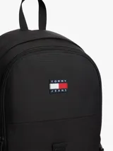 Mochila outdoor Tommy Jeans color negro, con compartimento principal, asa superior, correas ajustables y detalles de malla verde visible en los laterales. Incluye el parche con el logo de la marca bordado en el frente.