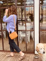 Bandolera color naranja de cuero con diseño capitoneado en forma de V.