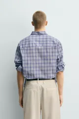 Camisa de corte relajado confeccionada en tejido de algodón, con estampado de cuadros en tonos azules. Presenta cuello abotonado, manga larga con puños abotonados y cierre frontal con botones.